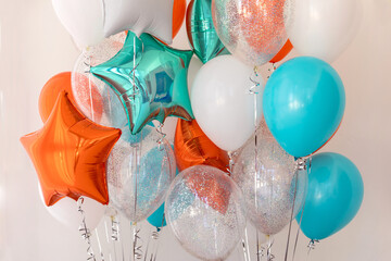 Composition of blue, silver, orange and transparent balloons with helium. Foil balloon in the shape of a star. The concept of decorating a room with helium balloons for holidays or birthdays - obrazy, fototapety, plakaty