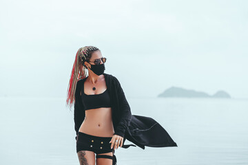 Beauty woman hair dreadlocks posing in the beach on mask, cyber style, USA, burning man, festival,...