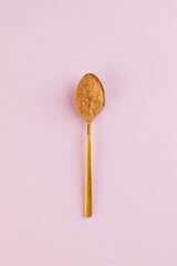 Coconut sugar in a Golden spoon on a pink background. Minimalism. The concept of healthy eating. Copy space.