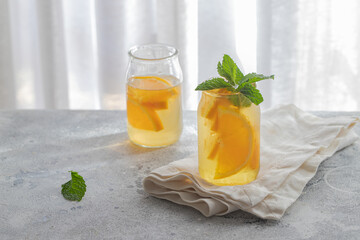Orange iced tea with mint  on concrete background. Refreshment beverage for summer hot days.