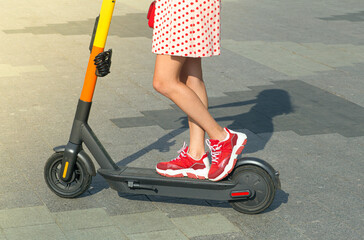 Girl on an electric scooter on a summer clear day in the city. Electric scooter rental and outdoor...