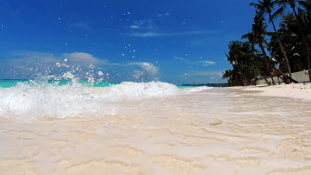 Close-up slow motion shot of sea waves breaking on sandy coastline. Boracay, Philippines.