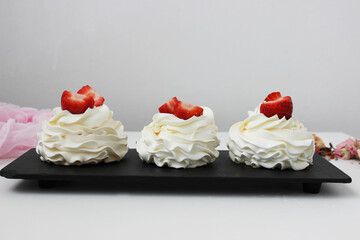 Cupcakes with white cream and strawberries on a black plate. Horizontal photo.