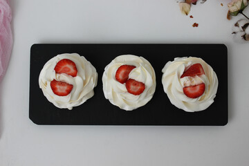 Cupcakes with white cream and strawberries on a black plate. Horizontal photo.