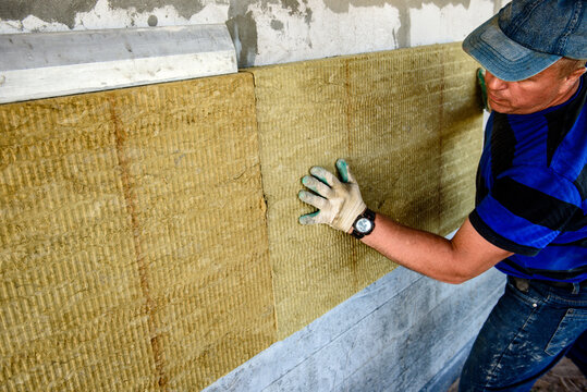 Worker insulates the house with mineral wool slabs. Internal thermal insulation of walls with mineral wool.