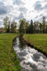 Mlynka stream with sky and trees mirroring on Park Bozeny Nemcove in Karvina city in Czech republic