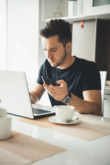 Brunette caucasian businessman with bristle working from home at the laptop and chatting on mobile