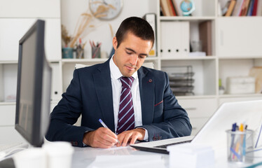 Successful businessman working with papers and laptop in office