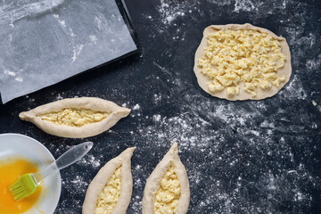 Rolled out piece of dough with cheese filling with ready raw khachapuri. Process of making bakery. Adjarian Khachapuri Recipe – Georgian cheese bread.