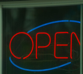 Open sign in neon red letters with blue circle open for business