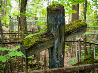 Naklejka premium An old unattended cross covered with green moss. Cross closeup in the cemetery