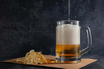 light beer with foam in a glass mug and Cecil cheese on a dark background. Concept of a cold amber drink.