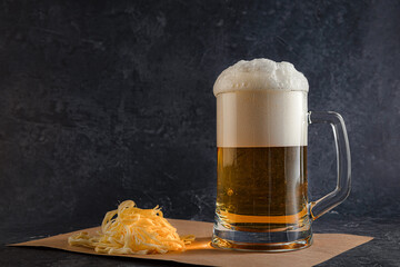 light beer with foam in a glass mug and Cecil cheese on a dark background. Concept of a cold amber...