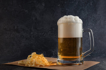 light beer with foam in a glass mug and Cecil cheese on a dark background. Concept of a cold amber...