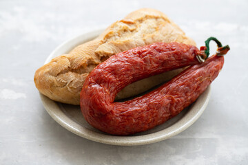 smoked sausage chourico with bread on dish on ceramic background