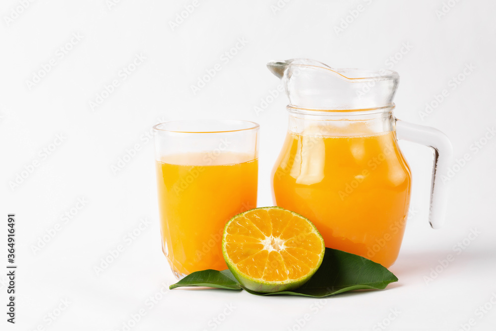 Wall mural Jug, glass of orange juice and orange fruits with green leaves  on white background