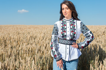 A young, pretty, pretty girl in a Ukrainian folk traditional shiny costume in a golden wheat field.