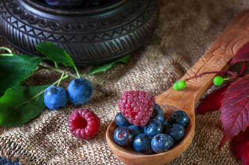 Ripe blueberries, raspberries and blueberries in a wooden spoon for making jam. Close-up, selective focus