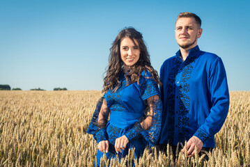 a young, pretty girl and a guy in Ukrainian folk traditional light embroidered clothes on a golden wheat field.