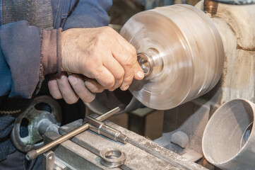 master grinds metal product. The old Metalworking machine, manufactured in the middle of the last century, is still in good condition.
