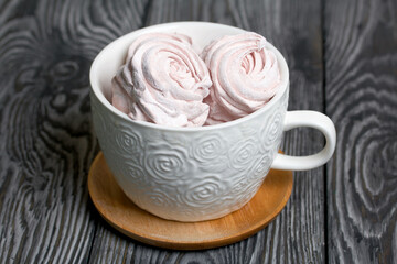 Homemade zephyr in a mug. On the surface of pine boards painted in black and white.