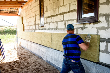 Worker insulates the house with mineral wool slabs. Internal thermal insulation of walls with...