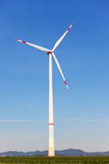 Windmill in front of a landscape with hills producing green electricity