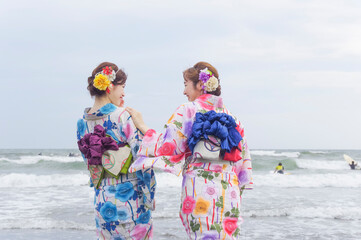 波打ち際で遊ぶ二人の浴衣の女性
