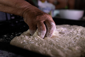 Dough for cake in the pan being stretched by a woman