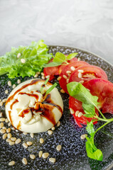 Burrata with pine nuts and balsamic with Cutlery top view. dinner with tomato and spinach salad with Italian Buratto cheese. The concept of healthy Mediterranean food