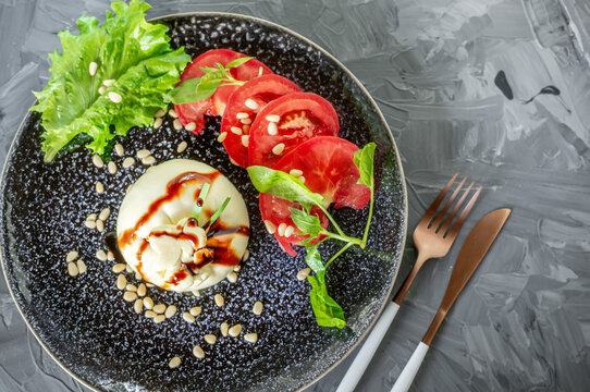 Burrata with pine nuts and balsamic with Cutlery top view. dinner with tomato and spinach salad with Italian Buratto cheese. The concept of healthy Mediterranean food