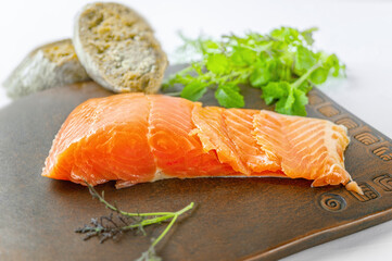 piece of smoked fresh salmon with lettuce leaves on a ceramic Board