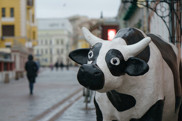 Sad cow figurine at the Moscow city street. Rainy spring day.