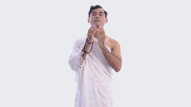 Muslim man praying wearing ihram isolated over white background