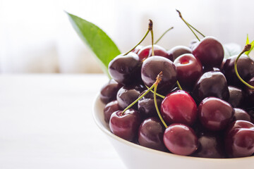 Cherry berries in a bowl on a white background. Fresh cherries. The concept of a healthy diet and support for local producers. Close-up. Copy space.