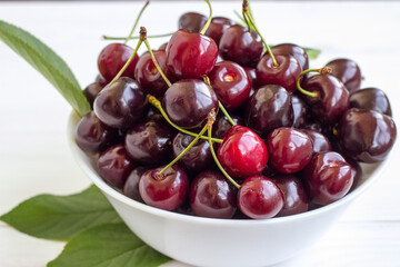 Cherry berries in a bowl on a white background. Fresh cherries. The concept of a healthy diet and support for local producers. Close-up.