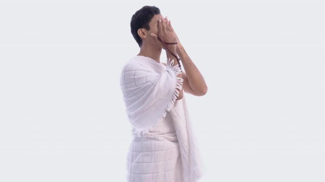 Muslim man praying wearing ihram isolated over white background