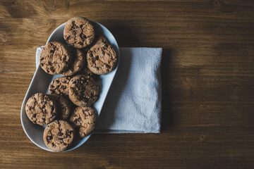 some chocolate cookies with a plate and a napkin on a wooden background