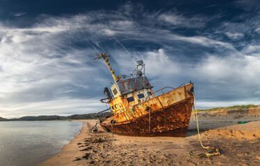 Naklejka premium An old shipwreck or wrecked boat abandoned stand on beach