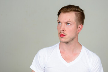 Portrait of young man with beard stubble wearing makeup