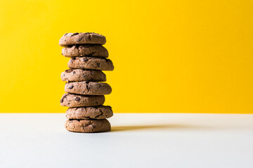a tower of  chocolate chip cookies on a yellow background