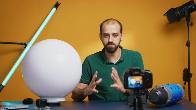 Videographer recording tutorial and explaining the use of china ball light modifier in video industry. Professional studio video and photo equipment technology for work, photo studio social media star