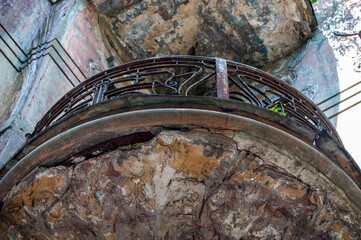 Balcony of an old building with traces of destruction, openwork forged railings in black, bottom view