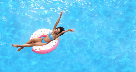 Excited young woman enjoying summer sun on inflatable ring at pool, above view. Empty space