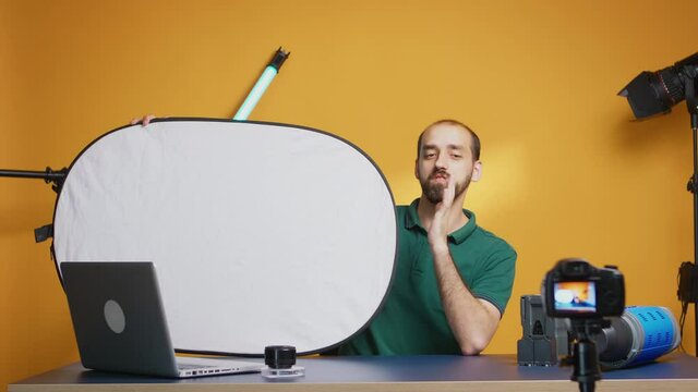 Photographer recording vlog about white light reflector in studio. Professional studio video and photo equipment technology for work, photo studio social media star and influencer