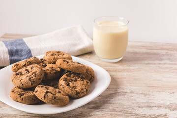 some chocolate cookies on a white plate with a glass of milk