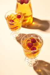 White wine sangria with nectarine and raspberries in glasses and a decanter on light background.