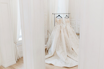 wedding dress on a hanger in a light studio.