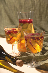 White wine sangria with nectarine and raspberries in glasses and a decanter on textile background.