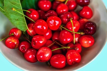 Glowy juicy cherries on white plate.